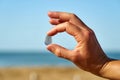 A person holds a single piece of blue sea glass between their finger and thumb