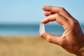 A person holds a single piece of white sea glass between their finger and thumb