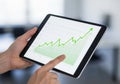 A person holds a tablet displaying a digital graph with a green upward trend line and data points Royalty Free Stock Photo