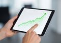 A person holds a tablet displaying a graph with a green upward trend line. The graph features Royalty Free Stock Photo