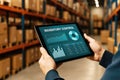 Person holding tablet displaying inventory control dashboard with charts and graphs in a warehouse image Royalty Free Stock Photo