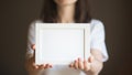 Person holds white frame in her hands. woman in white t-shirt on dark background. mockup fot text ad