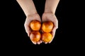 Person holging handful of blood oranges with red peel on black background