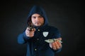 A person in a hoodie is aiming and holding the other hand with the dollar note.
