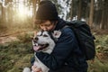 person hugs and kisses his black white dog in the forest