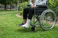 Person injured in a wheelchair. Foot and hand bandages, outdoor photography in a park