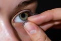 person inserting contact lens in eye, closeup