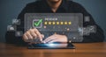 Person interacting with a digital review interface on a tablet with checkmark and stars displayed Royalty Free Stock Photo