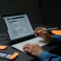 A person interacts with a digital tablet displaying a user interface design, using a stylus.