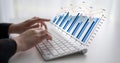 Hands typing on a keyboard while analyzing business data represented through vibrant graphs and charts demonstrating Royalty Free Stock Photo