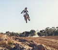 Person, jump and motorbike of professional motorcyclist in the air for trick, stunt or race on outdoor dirt track Royalty Free Stock Photo