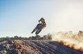 Person, jump and sports motorcyclist in the air for trick, stunt or race on outdoor dirt track. Rear view of expert Royalty Free Stock Photo