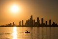 A person kayaking in the water at sunset with a city skyline silhouette in the background. Royalty Free Stock Photo