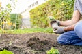 A person kneels in the soil, tending to a potted plant in the grassy landscape Royalty Free Stock Photo