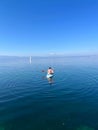 Person leisurely rowing a small white boat in a tranquil sea