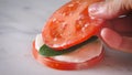 Person making a sandwich, tower Caprese salad with sliced tomatoes, cucumber, mozzarella and basil Royalty Free Stock Photo