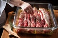 person marinating raw pork ribs for glazing