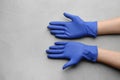 Person in medical gloves on light grey background, closeup of hands. Space for text Royalty Free Stock Photo