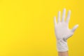 Person in medical gloves on yellow background, closeup of hand. Space for text Royalty Free Stock Photo