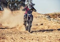 Person, motorcyclist and dust with motorbike on dirt track for race, extreme sports or outdoor competition. Professional Royalty Free Stock Photo