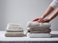 Person neatly folding and stacking soft neutral-colored linen fabrics on a white surface against a plain background for organized Royalty Free Stock Photo