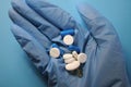 Person offers pills in blue glove. Medications for taking against COVID-19 Royalty Free Stock Photo