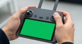 Person operating a drone remote controller with a green screen display for aerial footage Royalty Free Stock Photo