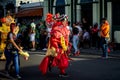 Person in orange costume pass by city street full of people at dominican carnival