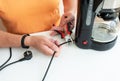 Person in orange shirt cutting coffee maker s power cord with pliers, promoting electrical safety. Royalty Free Stock Photo