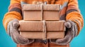 Person in orange sweater and gloves holding a stack of wrapped cardboard gift boxes with string Royalty Free Stock Photo