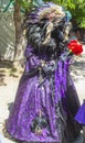 Person in ornate costume with Raven head and beak and American Indian styled feather headress and purple brocade dress at Oklahoma