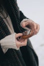 Person outdoors, holding a small acoustic music player in snowy weather