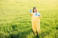 Person in overalls holds paper with a call to save the planet while standing on green field on sunset and the other hand shows a Royalty Free Stock Photo