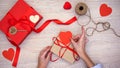 Person packing b-day present, putting red paper heart on craftbox Valentines day