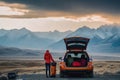 person, packing up car for epic road trip adventure, with view of mountains in the background