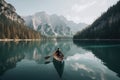 person, paddling through calm lake, surrounded by majestic mountains