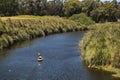 Person paddling a canoe down a scenic river surrounded by lush greenery.
