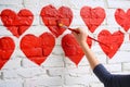 person painting vibrant red hearts on a white brick wall