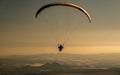 Person paragliding above the mountains under the sunlight during the sunset