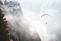 Person paragliding through the air above majestic snow-capped mountain peaks