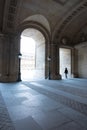 Person passing through the archway of the Louvre Museum