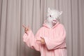 Person in pink hoodie with lama head pointing back on studio wall background