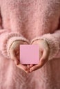 A person in a pink sweater holding up an empty piece of paper, AI