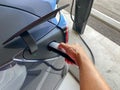 A person plugging in a gray Tesla to a charging station