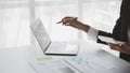 Person pointing at laptop screen, businessman sitting at company, looking at financial information on laptop summarized by the Royalty Free Stock Photo