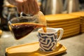 Person pouring coffee in a mug on a wooden tray Royalty Free Stock Photo