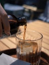 Person pouring a cold, refreshing coffee brew into a clear glass from a bottle Royalty Free Stock Photo