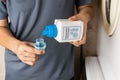 Person pouring concentrated liquid laundry detergent into measurement cap