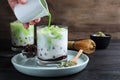 Person pouring green matcha into glass with milk bubble tea at black wooden table, closeup Royalty Free Stock Photo