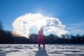 person pouring hot water up in the sky  sunny winter day. Boiling water challenge  which instantly freezes  turns into snow if the Royalty Free Stock Photo